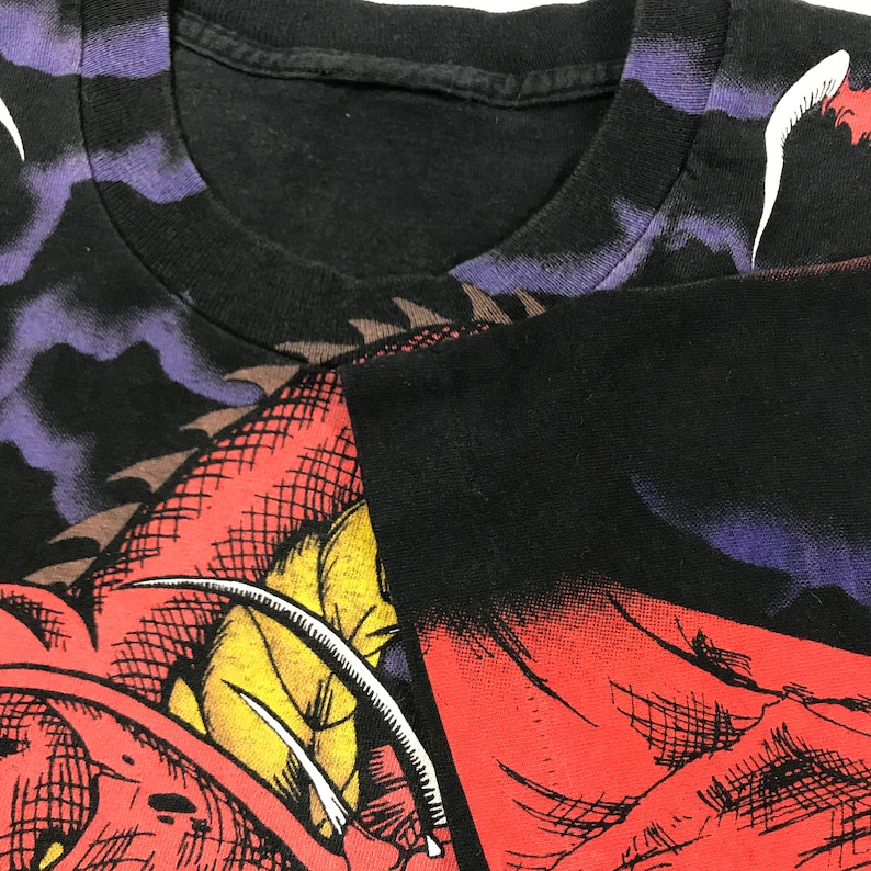 May include: Black t-shirt featuring a red, yellow and white dragon graphic print. The dragon has sharp claws and teeth. The shirt has a distressed look.