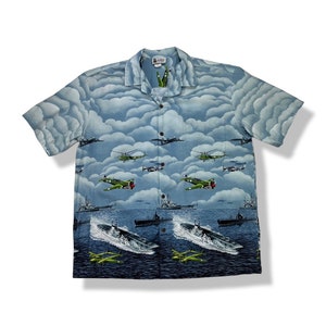 May include: A blue short-sleeved button-up shirt with a print of aeroplanes, helicopters, and battleships against a cloudy sky.