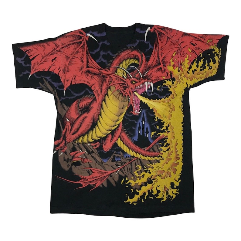 May include: Black t-shirt featuring a red dragon breathing fire. The dragon is surrounded by flames and a dark castle in the background.