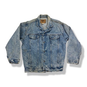 May include: A light blue denim jacket with a faded look. The jacket has a button closure, two chest pockets, and two front pockets. The label on the jacket reads "Denver Hayes".