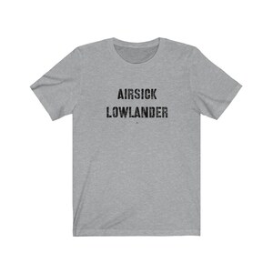 May include: A gray t-shirt with the text "AIR SICK LOWLANDER" printed in black.