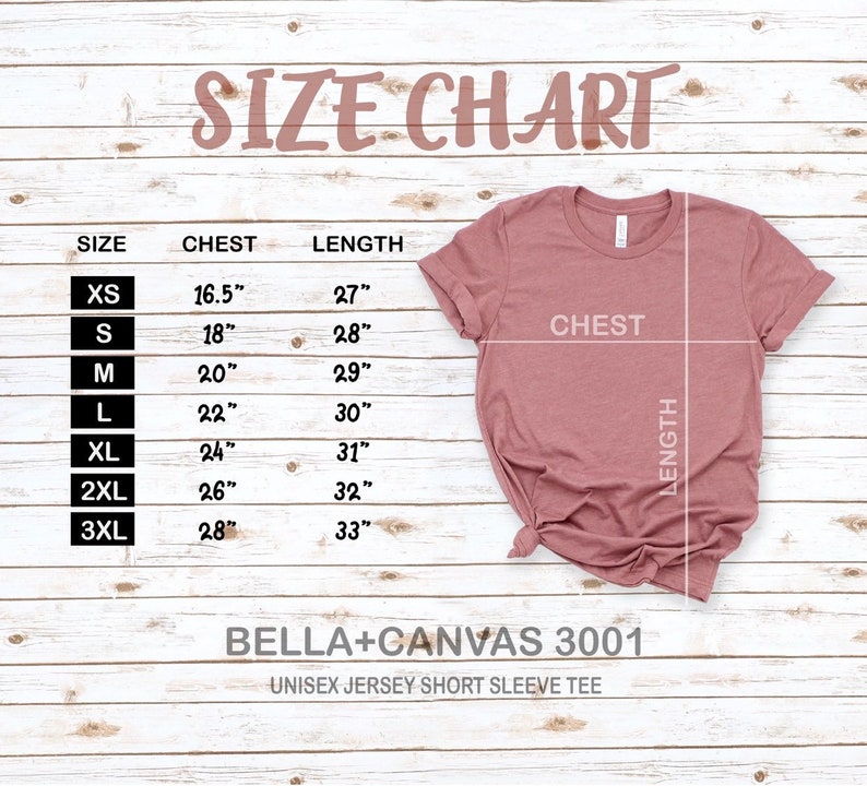 May include: Size chart for a unisex jersey short sleeve tee, showing chest and length measurements in inches for sizes XS to 3XL. The chart is printed on a light wood background with a pink t-shirt displayed next to it.