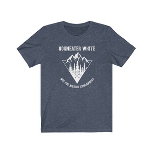 May include: A dark blue t-shirt with a white graphic design of a mountain range with a triangle around it. The text "Horneater White" is above the mountain range and the text "Not for airsick lowlanders" is below the mountain range.