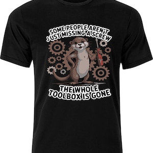 Könnte beinhalten: Schwarzes T-Shirt mit einem Cartoon-Otter, der einen Schraubendreher hält und von Zahnrädern umgeben ist. Der Text lautet "SOME PEOPLE AREN'T JUST MISSING A SCREW" und "THE WHOLE TOOLBOX IS GONE".