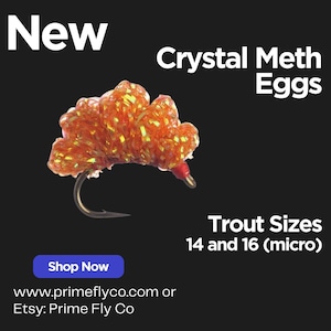May include: An orange and yellow fishing lure with the text "Crystal Meth Eggs" and "Trout Sizes 14 and 16 (micro)". The lure is on a black background with the text "New" and a blue "Shop Now" button.
