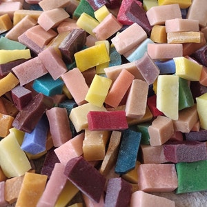 Könnte beinhalten: Eine Sammlung kleiner, rechteckiger Mosaikfliesen in verschiedenen Farben, darunter Rot, Blau, Grün, Gelb, Braun und Weiß. Die Fliesen sind in einem zufälligen Muster angeordnet und schaffen eine optisch ansprechende und strukturierte Oberfläche.