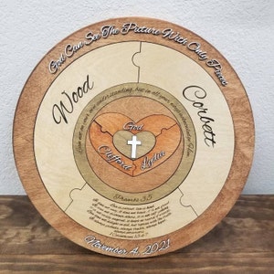 May include: A wooden puzzle with a heart in the center. The heart is divided into two pieces with the names "Clifford" and "Lydia" on them. The heart is surrounded by a larger circle with the names "Wood" and "Corbett" on it. The puzzle also includes the text "God Can See The Picture With Only Pieces" and a Bible verse from Proverbs 3:5. The date "November 4, 2021" is also included.