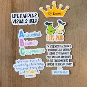 K&ouml;nnte beinhalten: Eine Sammlung bunter Aufkleber mit verschiedenen Designs und Texten. Einer der Aufkleber lautet: "LIFE HAPPENS, VISUALS HELP." Ein anderer zeigt eine goldene Krone mit "R+ Queen." Weitere Aufkleber zeigen Birnen, das ABC und Zitate &uuml;ber Verhalten und Lernen.