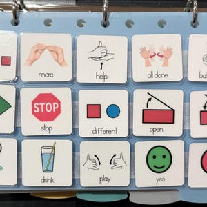 May include: A communication board with various picture symbols. The images include words like "I want", "go", "eat", and "drink", along with symbols for "help", "stop", and "play". The board is designed to aid communication.