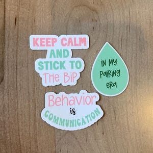 K&ouml;nnte beinhalten: Eine Auswahl an Aufklebern mit motivierenden Spr&uuml;chen. Einer der Aufkleber lautet "Keep Calm and Stick to The BIP" in Rosa und Gr&uuml;n. Ein anderer besagt "Behavior is Communication". Ein gr&uuml;ner Tropfenaufkleber tr&auml;gt die Aufschrift "In my Pairing Era".