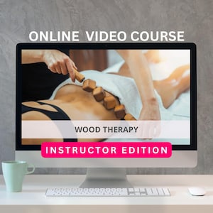 May include: A computer monitor displays an online video course on wood therapy. The screen shows a person receiving a massage with wooden tools. The text on the screen reads "ONLINE VIDEO COURSE", "WOOD THERAPY", and "INSTRUCTOR EDITION". A light green mug, keyboard, and mouse are on the desk.