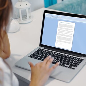 May include: A person working on a laptop computer with a white background. The laptop screen shows a document with text.