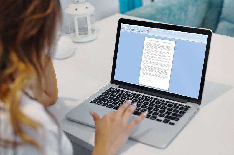 May include: A person working on a laptop computer with a white background. The laptop screen shows a document with text.