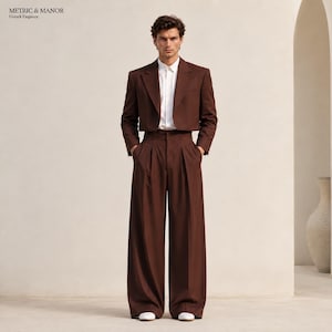 May include: A dark brown cropped blazer and matching high-waisted wide-leg trousers worn with a crisp white button-down shirt. The ensemble features clean lines and a structured fit. The text METRIC & MANOR Unlock Elegance is visible.