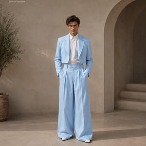 May include: A light blue cropped blazer with long sleeves and a white button-down shirt underneath, paired with matching light blue high-waisted wide-leg trousers featuring front pleats. The text Metric & Manor Unlock Elegance is visible.