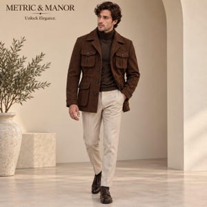 May include: A brown field jacket with four front pockets and a button-up front, worn over a dark brown turtleneck sweater and light beige trousers. The outfit is completed with dark brown leather shoes. Text reads METRIC & MANOR Unlock Elegance.