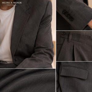 May include: A charcoal grey suit featuring a blazer with a single button closure and a white undershirt. The suit includes detailed views of the sleeve cuffs with four buttons, pleated trousers with a waistband, and a close-up of the fabric texture.