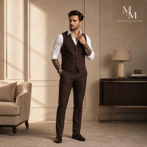 Puede incluir: Un traje marrón de tres piezas con una camisa blanca. El traje incluye un chaleco, un pantalón y una chaqueta a juego. El modelo lleva un reloj y zapatos de vestir. El logotipo "Metric & Manor" es visible en el fondo.