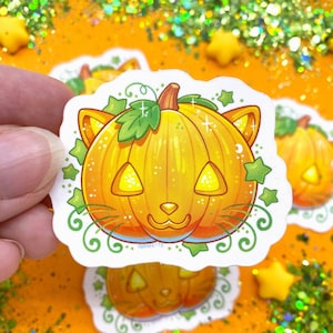 May include: A sticker featuring a cartoon pumpkin with cat ears and a smiling face. The pumpkin is orange with a green stem and leaves. The background is white with green vines and stars.