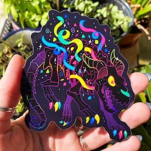 May include: A black and purple sticker with a skeleton of a creature with neon green, blue, pink, and yellow ribbons and confetti. The sticker has a holographic finish.