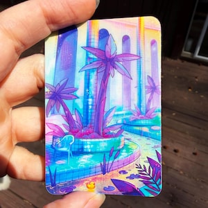 May include: A rectangular card featuring a vibrant, colorful illustration of a pool area with palm trees, a small blue chair, and a tiny yellow rubber duck. The scene uses a palette of bright pink, purple, blue, and yellow with a sparkling effect.