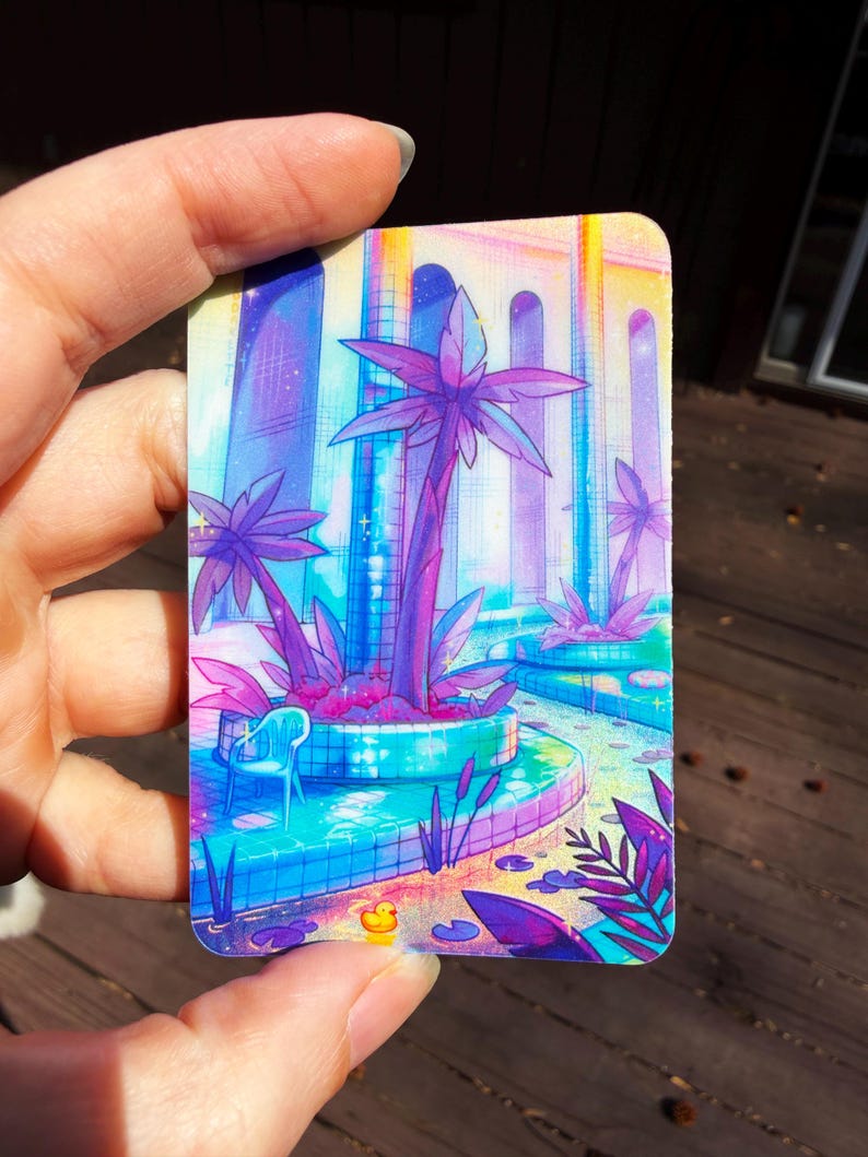 May include: A rectangular card featuring a vibrant, colorful illustration of a pool area with palm trees, a small blue chair, and a tiny yellow rubber duck. The scene uses a palette of bright pink, purple, blue, and yellow with a sparkling effect.
