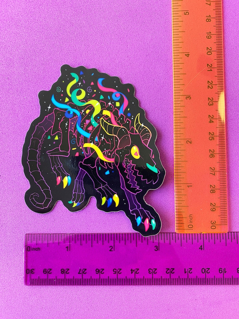 May include: A black and white sticker of a skeleton monster with neon colored details. The monster is surrounded by confetti and streamers. The sticker is approximately 3 inches tall.