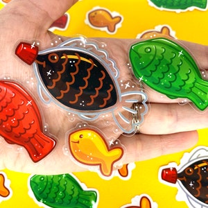May include: A set of six colorful fish-shaped stickers with glitter accents. The stickers feature a variety of fish designs, including a red fish, a green fish, a gold fish, and a black fish with a bottle of soy sauce.