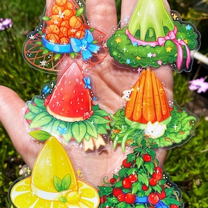 May include: A collection of whimsical stickers featuring various food-themed hats. Designs include a hat of oranges with a blue bow, a green hat with a pink ribbon, a strawberry hat, a carrot hat with a bunny, a lemon hat, and a cherry tree hat.