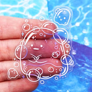 May include: A clear sticker featuring a whimsical design of a face surrounded by bubbles. The face has a simple, minimalist style with delicate lines and a touch of purple. The bubbles are outlined in white, creating a playful and ethereal effect.