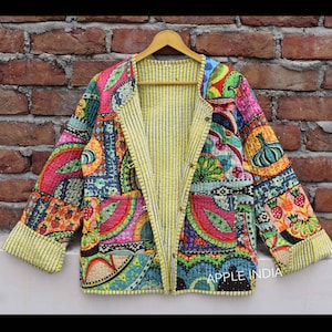 Könnte beinhalten: Eine bunte Patchworkjacke mit gelbem gestreiftem Futter. Die Jacke hat eine Vielzahl von floralen und geometrischen Mustern in den Farben Rosa, Blau, Grün und Rot. Die Jacke ist aus Baumwolle und hat einen Knopfverschluss. Der Text "APPLE INDIA" ist in der rechten unteren Ecke der Jacke sichtbar.