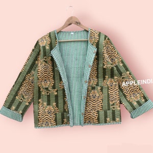 May include: A reversible quilted jacket with a green and white striped pattern on one side and a green and brown tiger print on the other side. The jacket has a button closure and two pockets.