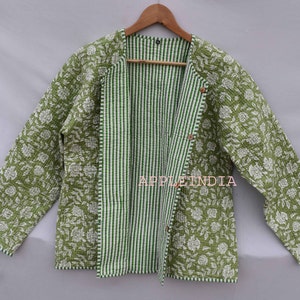 Può includere: Una giacca trapuntata verde con stampa floreale bianca e fodera a righe. La giacca ha una chiusura a bottone ed è realizzata in cotone.