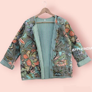 Peut inclure: Une veste matelassée réversible avec un imprimé floral d'un côté et un motif rayé de l'autre. La veste est verte et a une coupe décontractée.