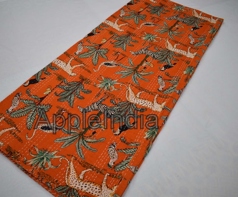 Puede incluir: Colcha kantha naranja con un patr&oacute;n repetido de animales y plantas. La colcha presenta cebras, leopardos, p&aacute;jaros y palmeras.