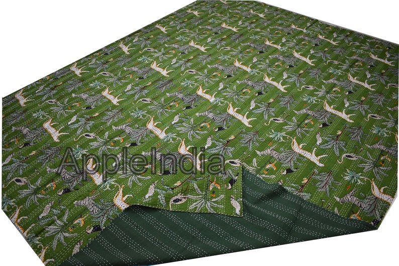 Puede incluir: Colcha kantha verde con un dise&ntilde;o de estampado de animales blanco y negro. La colcha est&aacute; doblada por la mitad, mostrando el lado inferior a rayas verdes y blancas.