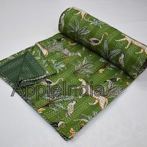 Puede incluir: Colcha kantha verde con estampado de animales de la selva con cebras, leopardos, tucanes y palmeras. La colcha est&aacute; doblada y enrollada.