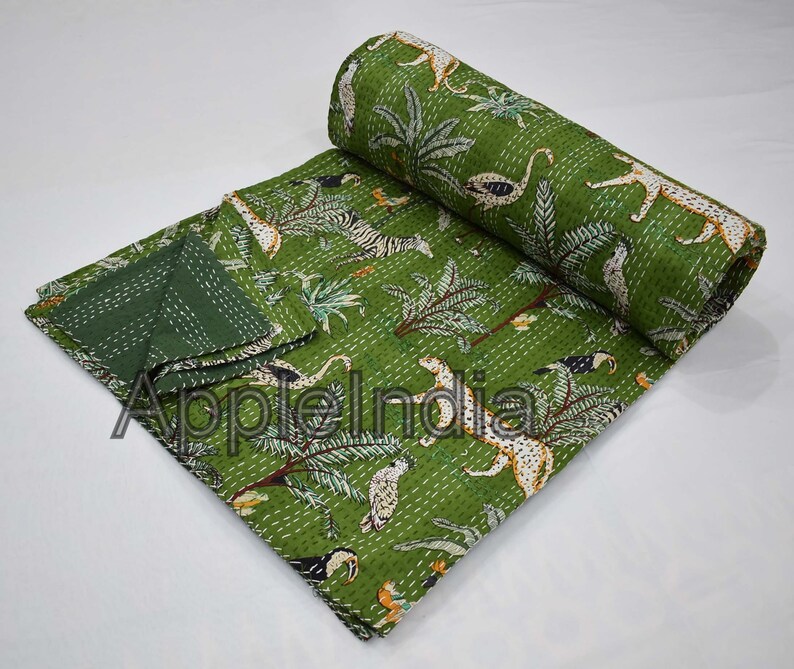 Puede incluir: Colcha kantha verde con estampado de animales de la selva con cebras, leopardos, tucanes y palmeras. La colcha est&aacute; doblada y enrollada.