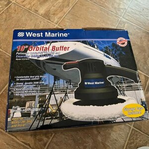 May include: A West Marine 10-inch orbital buffer in a box. The box features a picture of a boat being buffed. The buffer has a black body, a white buffing pad, and a dual grip design. The box text includes "Buffs, Waxes and Polishes!"