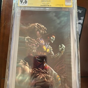 Puede incluir: Un cómic calificado en una caja protectora. El cómic es Darkness #1, firmado por Ron Marz, y calificado 9.6 por CGC. La portada presenta una ilustración oscura y de fantasía de un guerrero con un dragón.