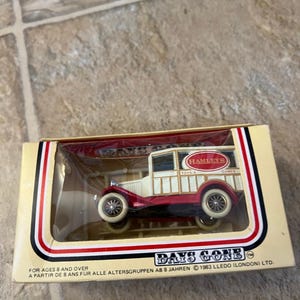 May include: A vintage toy truck in a box. The truck is red and white with gold trim and the Hamleys logo. The box has the Days Gone logo and text that reads "For Ages 8 and Over."