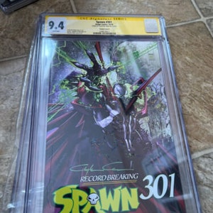May include: A graded comic book in a protective plastic case. The comic book is Spawn #301, a record-breaking issue. The cover features a black and green character with a red cape and the text "Spawn" in yellow letters.