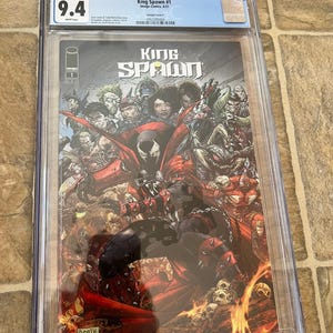 May include: A CGC graded comic book titled "King Spawn #1" with a 9.4 grade. The cover art features a dynamic illustration of Spawn and other characters in a fiery, action-packed scene. The comic is encased in a protective plastic holder.