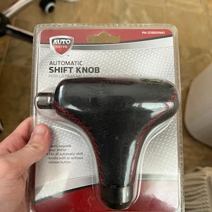 May include: An Auto Drive automatic shift knob in its original packaging. The black knob has red stitching and is designed to easily upgrade a vehicle's shifter. The packaging includes the text "AUTOMATIC SHIFT KNOB".