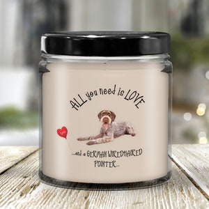 May include: A white candle with a black lid and a brown and white German Wirehaired Pointer dog illustration. The candle has the text "All you need is love... and a German Wirehaired Pointer..." printed on it.