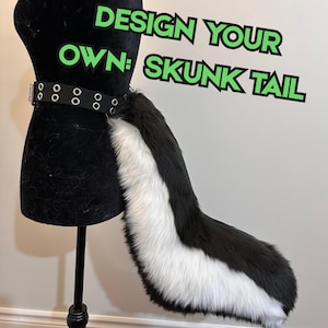 May include: A faux fur skunk tail in black and white attached to a black belt with silver-toned metal grommets. The text DESIGN YOUR OWN: SKUNK TAIL is displayed in green letters with a black outline against the plain background.
