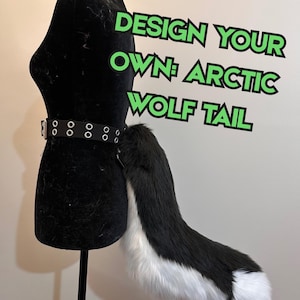 May include: A black and white faux fur wolf tail attached to a black belt with silver-toned metal grommets. The text "DESIGN YOUR OWN: ARCTIC WOLF TAIL" is displayed in green letters with a black outline against the plain background.