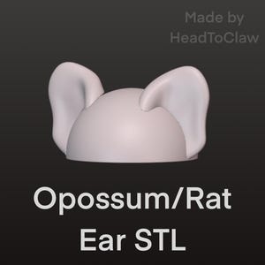 May include: A 3D-rendered, light-colored opossum or rat ear STL file. The image features a pair of large, upright ears attached to a rounded base. The text "Opossum/Rat Ear STL" is displayed in white, along with "Made by HeadToClaw".