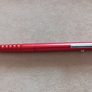 May include: A red mechanical pencil with a silver clip and a silver tip. The pencil has a textured grip.