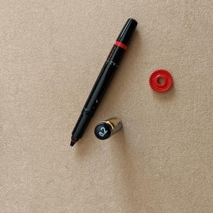 Könnte beinhalten: Ein schwarzer und roter Stift mit einer silbernen Kappe und einer roten Kappe. Der Stift hat die Nummer "02" auf der Kappe.